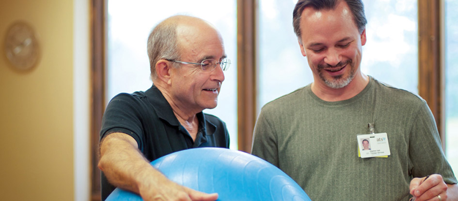 resident holding exercise ball and another man