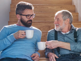 Adult child smiling at dad over coffee cup